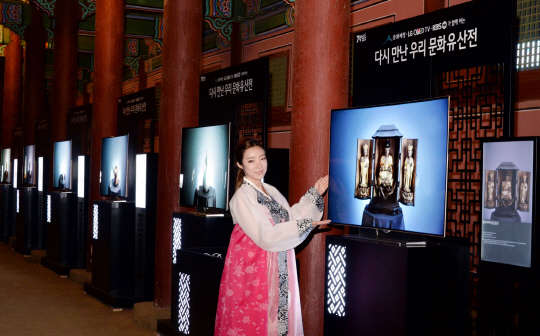 17일 모델이 경복궁 근정전 회랑에서 일본 고려미술관에 전시한 목조아미타삼존불감을 올레드TV의 화면으로 소개하고 있다.  LG전자 제공